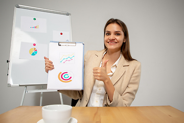 Image showing Young woman talking, working during videoconference with colleagues at home office