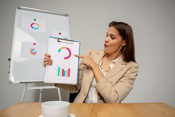 Image showing Young woman talking, working during videoconference with colleagues at home office