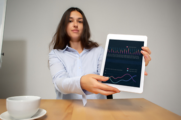 Image showing Young woman talking, working during videoconference with colleagues at home office