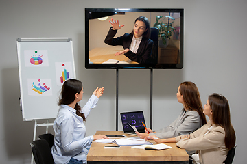 Image showing Young women talking, working during videoconference with colleagues at office or living room