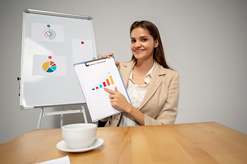 Image showing Young woman talking, working during videoconference with colleagues at home office