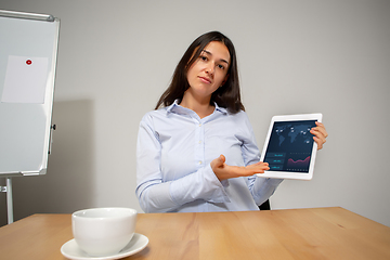 Image showing Young woman talking, working during videoconference with colleagues at home office