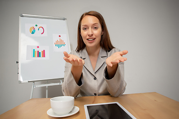 Image showing Young woman talking, working during videoconference with colleagues at home office