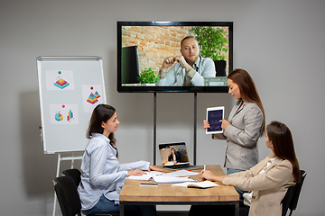 Image showing Young women talking, working during videoconference with colleagues at office or living room