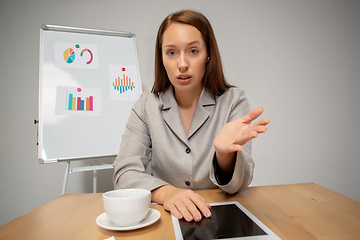 Image showing Young woman talking, working during videoconference with colleagues at home office