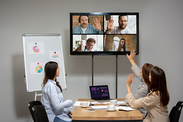 Image showing Young women talking, working during videoconference with colleagues at office or living room