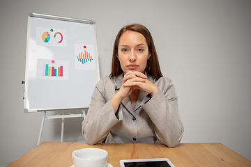 Image showing Young woman talking, working during videoconference with colleagues at home office