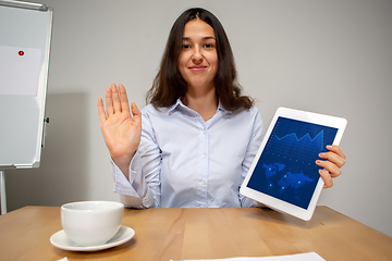 Image showing Young woman talking, working during videoconference with colleagues at home office