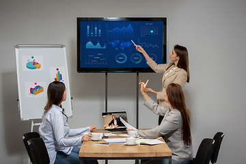 Image showing Young women talking, working during videoconference with colleagues at office or living room