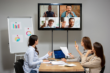 Image showing Young women talking, working during videoconference with colleagues at office or living room