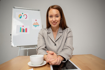 Image showing Young woman talking, working during videoconference with colleagues at home office