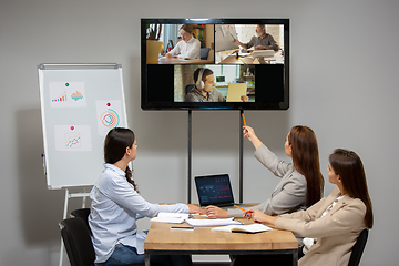 Image showing Young women talking, working during videoconference with colleagues at office or living room