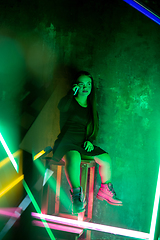 Image showing Caucasian female inclusive model posing on studio background in neon light