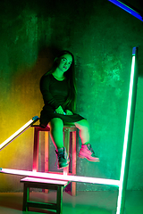 Image showing Caucasian female inclusive model posing on studio background in neon light