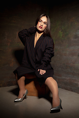 Image showing Caucasian female inclusive model posing on dark studio background in classic black outfit