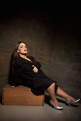 Image showing Caucasian female inclusive model posing on dark studio background in classic black outfit