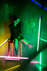 Image showing Caucasian female inclusive model posing on studio background in neon light