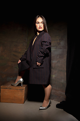 Image showing Caucasian female inclusive model posing on dark studio background in classic black outfit