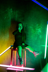 Image showing Caucasian female inclusive model posing on studio background in neon light