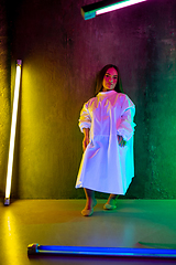 Image showing Caucasian female inclusive model posing on studio background in neon light