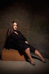 Image showing Caucasian female inclusive model posing on dark studio background in classic black outfit