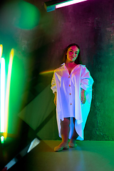 Image showing Caucasian female inclusive model posing on studio background in neon light