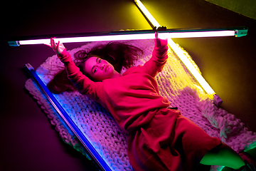 Image showing Caucasian female inclusive model posing on studio background in neon light