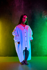 Image showing Caucasian female inclusive model posing on studio background in neon light