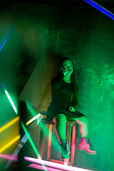 Image showing Caucasian female inclusive model posing on studio background in neon light