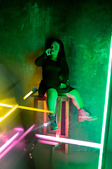 Image showing Caucasian female inclusive model posing on studio background in neon light