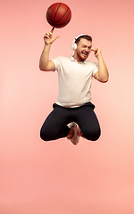 Image showing Full length portrait of young successfull high jumping man gesturing isolated on pink studio background