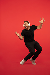 Image showing Full length portrait of young successfull high jumping man gesturing isolated on red studio background