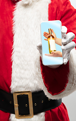 Image showing Close up hands of Santa Claus holding device with hands giving wine on the screen