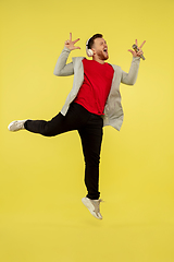 Image showing Full length portrait of young successfull high jumping man gesturing isolated on yellow studio background