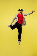 Image showing Full length portrait of young successfull high jumping man gesturing isolated on yellow studio background