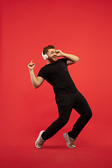 Image showing Full length portrait of young successfull high jumping man gesturing isolated on red studio background