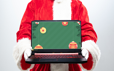 Image showing Close up hands of Santa Claus holding device with stylish decoration on the screen, copyspace