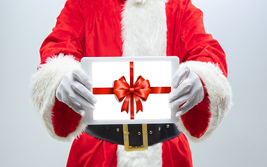 Image showing Close up hands of Santa Claus holding device with gift decoration on the screen