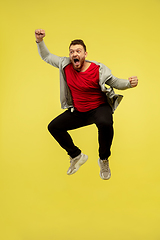 Image showing Full length portrait of young successfull high jumping man gesturing isolated on yellow studio background