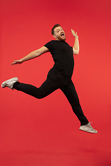 Image showing Full length portrait of young successfull high jumping man gesturing isolated on red studio background