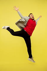 Image showing Full length portrait of young successfull high jumping man gesturing isolated on yellow studio background