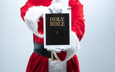 Image showing Close up hands of Santa Claus holding device with Bible on the screen