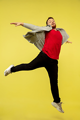 Image showing Full length portrait of young successfull high jumping man gesturing isolated on yellow studio background