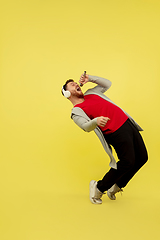 Image showing Full length portrait of young successfull high jumping man gesturing isolated on yellow studio background