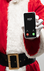 Image showing Close up hands of Santa Claus holding device with incoming call from 2021 year