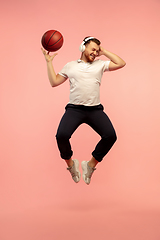 Image showing Full length portrait of young successfull high jumping man gesturing isolated on pink studio background