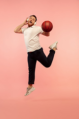 Image showing Full length portrait of young successfull high jumping man gesturing isolated on pink studio background