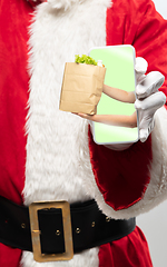 Image showing Close up hands of Santa Claus holding device with hands giving food on the screen