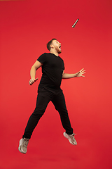Image showing Full length portrait of young successfull high jumping man gesturing isolated on red studio background