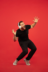 Image showing Full length portrait of young successfull high jumping man gesturing isolated on red studio background